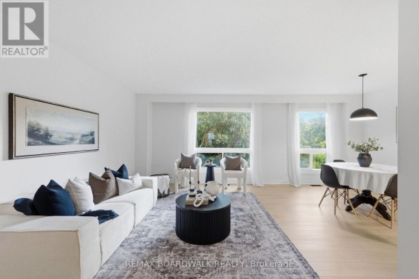 Living room with a white sectional sofa, dark coffee table, and large windows. - 14 - 314 Stone Quarry Private, Ottawa