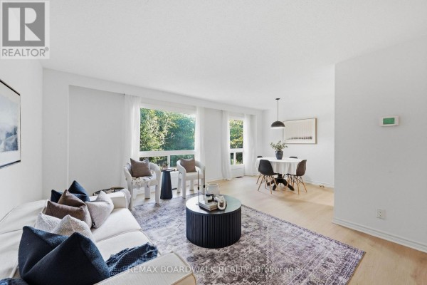 Living and dining area with light wood floors, white walls, and large windows. - 14 - 314 Stone Quarry Private, Ottawa