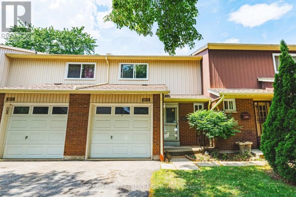 Close-up exterior view of a townhouse unit with brick and wood siding, two garages, and a front door. - 14 - 564 Sheraton Road, Burlington