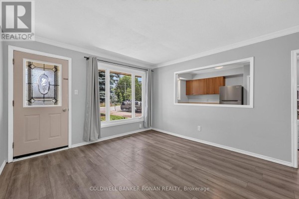 Living room showing a beige front door with stained glass, a large bay window, and grey curtains. - 14 & 16 Fletcher Street, New Tecumseth