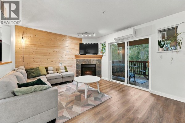 Living room with sectional sofa, fireplace, wood wall, and sliding glass door to a deck. - 14 1450 Vine Road Road, Pemberton