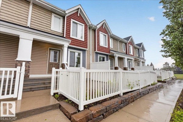 Front view of townhouses with white fences and landscaping under a cloudy sky. - #14 1508 105 St Nw, Edmonton