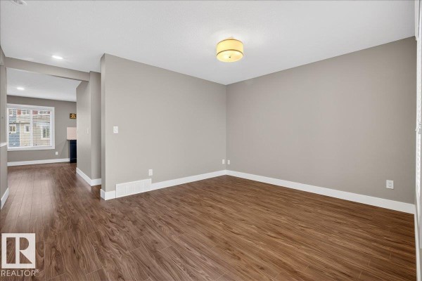 Living room with neutral-colored sofa, armchairs, coffee table, rug, and decorative mirror. - #14 1508 105 St Nw, Edmonton