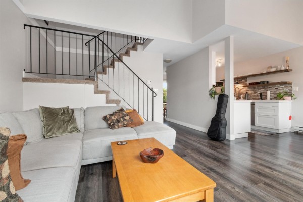 Living room with a sectional sofa, stairs, and a view into the kitchen area. - 14 1829 Heath Road, Agassiz, Agassiz