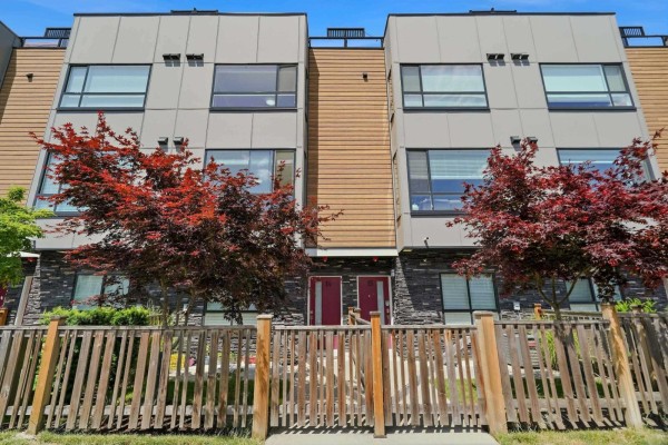 A bright living room with light wood floors, grey sectional sofa, coffee table, and television, overlooking a street view. - 14 19631 55a Avenue, Langley