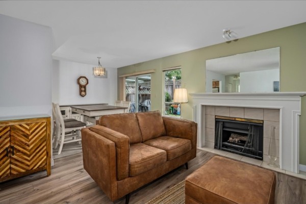 Living room with brown sofa, fireplace, dining table, and sliding glass doors to patio. - 14 32165 7th Avenue, Mission