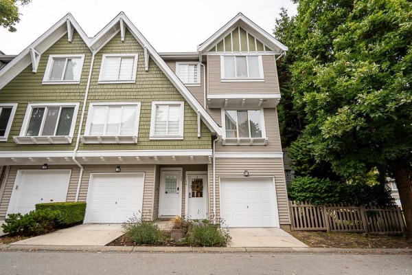 Exterior of townhouses with peaked roofs, green and beige siding, and attached garages. - 14 8775 161 Street, Surrey