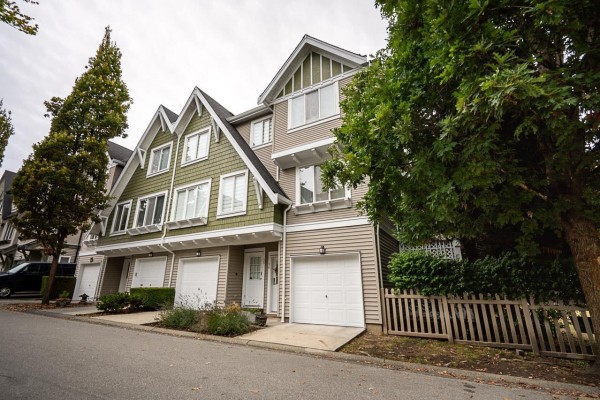 Corner view of townhouses with garages, green and beige siding, and mature trees. - 14 8775 161 Street, Surrey