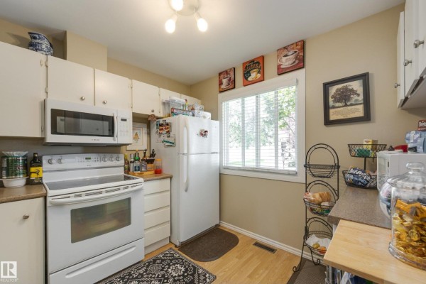 View of a kitchen with white cabinets, a white refrigerator, and a window. - #14 9619 180 St Nw, Edmonton