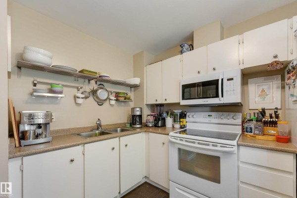 A corner kitchen with white cabinets, a double sink, and a white stove. - #14 9619 180 St Nw, Edmonton
