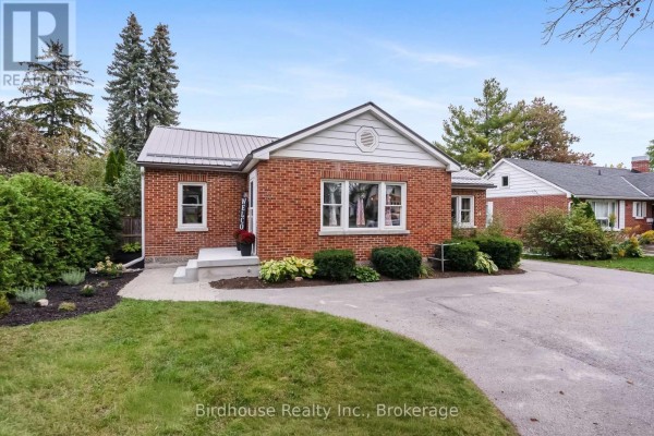 Front entrance of a red brick bungalow with a concrete walkway, steps, and a welcome sign. - 14 Angeline Street S, Kawartha Lakes