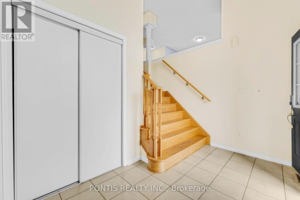 Interior view of a home's entrance hall with tiled floor, closet, and wooden staircase. - 14 Arrowstone Court, Brampton