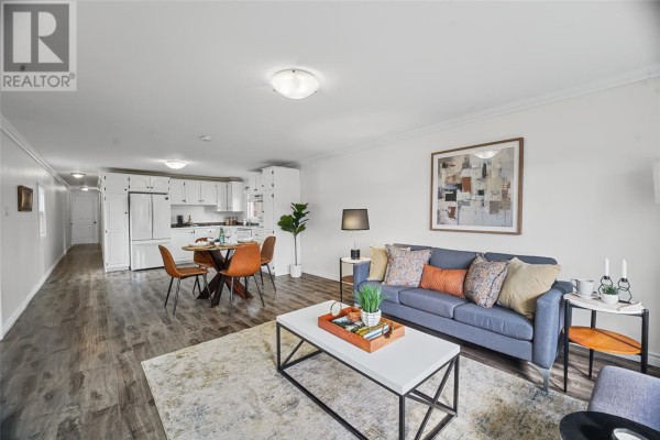 Open concept living room and kitchen with white cabinetry, a dining table, and a grey sofa. - 14 Ashgrove Drive, Paradise