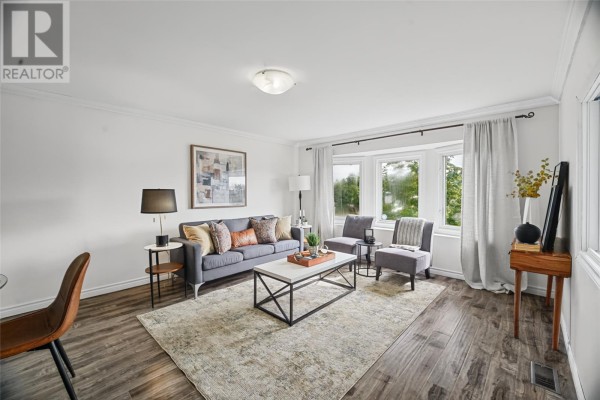 Living room area with a grey sofa, coffee table, bay windows with curtains, and framed artwork. - 14 Ashgrove Drive, Paradise