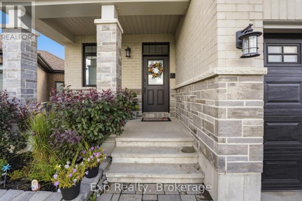 Concrete steps leading to a dark front door with a wreath, flanked by stone pillars. - 14 Athabaska Drive, Belleville