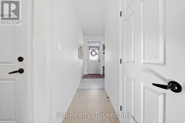 Hallway inside the house with white walls, light wood floors, and closed white doors. - 14 Athabaska Drive, Belleville