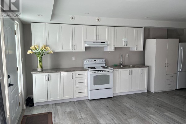 Kitchen with white cabinetry, granite countertops, a white stove, and a stainless steel sink. - 14 #basement - 3029 Finch Avenue W, Toronto