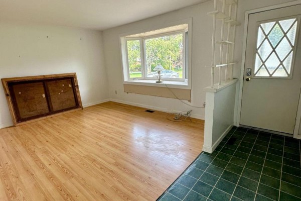 Interior living room with light wood laminate flooring and a large bay window. - 14 Brock Crescent, Collingwood