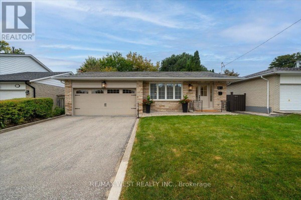 Front exterior of a brick and stone bungalow with a double garage. - 14 Burnhamill Place, Toronto