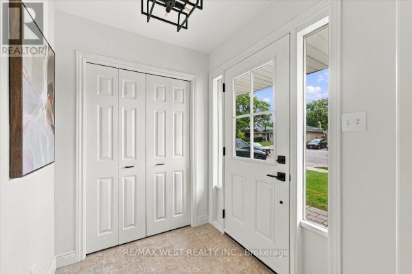 Interior foyer with double white bi-fold doors, beige door, and tiled floor. - 14 Burnhamill Place, Toronto