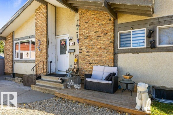 Close-up of the front entrance with stone accents, porch seating, and decorative items. - 14 Circlewood Dr, Sherwood Park