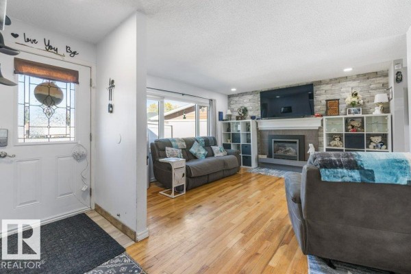 Entryway leading to a living room with hardwood floors, fireplace, and sectional sofa. - 14 Circlewood Dr, Sherwood Park