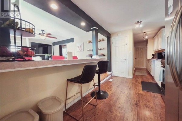 Kitchen with a breakfast bar, two black bar stools, and white cabinets. View of dining area. - 14 Collins, Copper Cliff