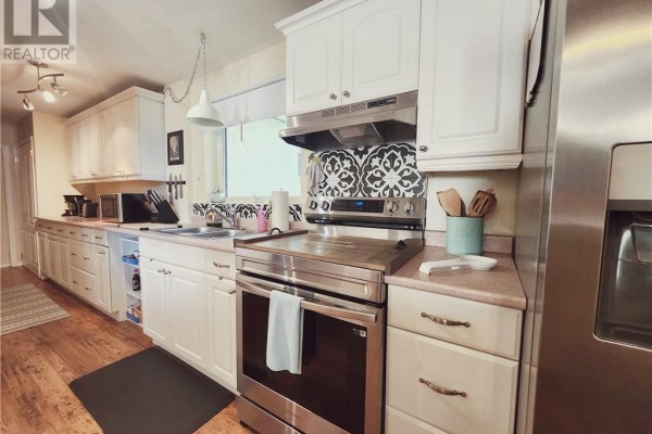 Kitchen with white cabinets, stainless steel appliances, a patterned backsplash, and a window. - 14 Collins, Copper Cliff