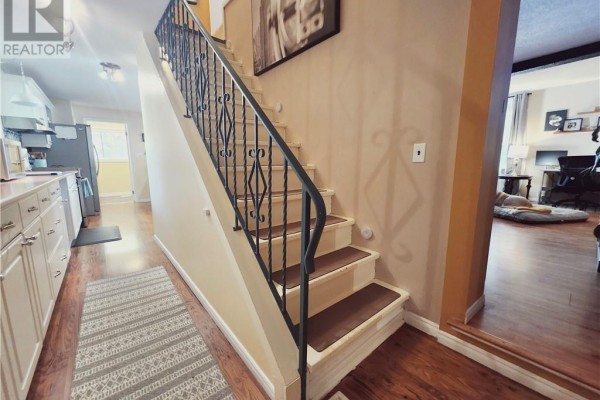 Interior view of a staircase with black metal railings and beige walls, leading to a living area. - 14 Collins, Copper Cliff