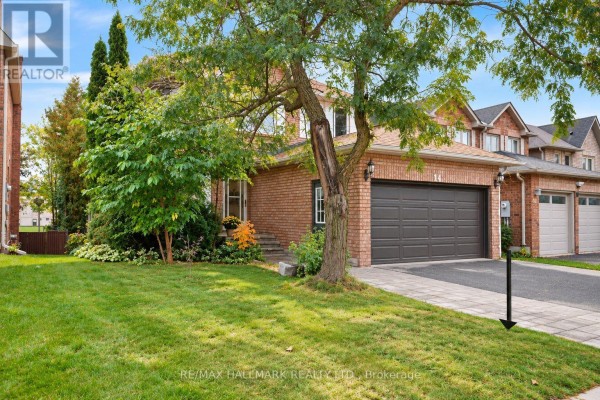 Side exterior view of a brick house with a lawn and mature tree. - 14 Crawford Rose Drive, Aurora