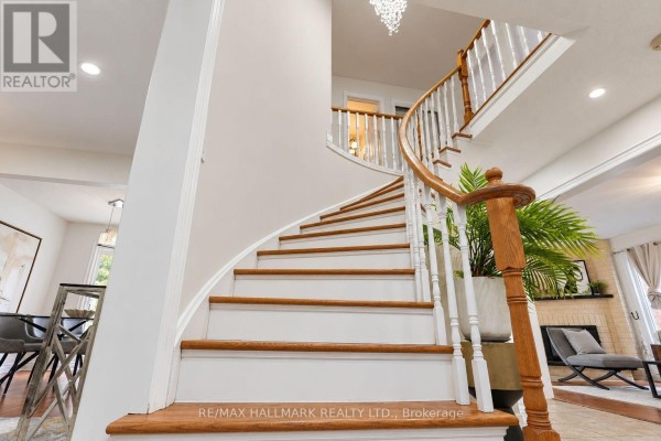 Interior spiral staircase with white railings, wooden steps, and a chandelier above. - 14 Crawford Rose Drive, Aurora