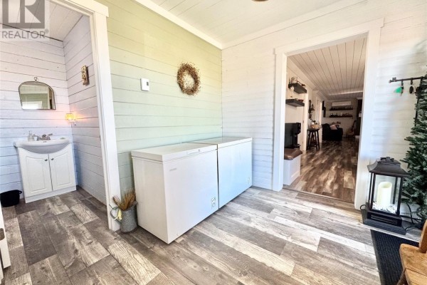 Interior view of a hallway with two white chest freezers, a small vanity, and doorways. - 14 Durrell Street, Twillingate