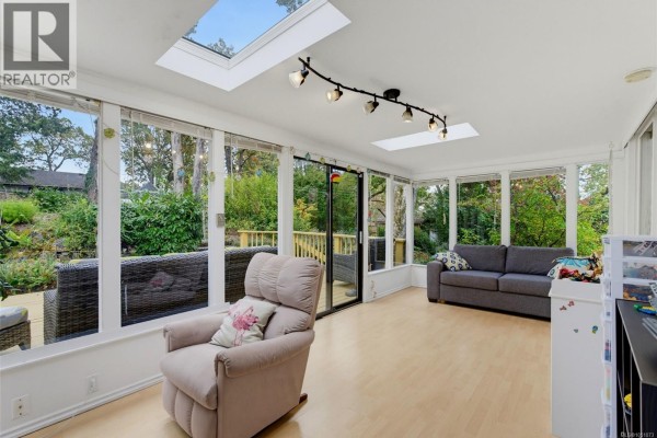 Sunroom with floor-to-ceiling windows, skylights, light wood floors, and seating. - 14 Eaton Ave, View Royal
