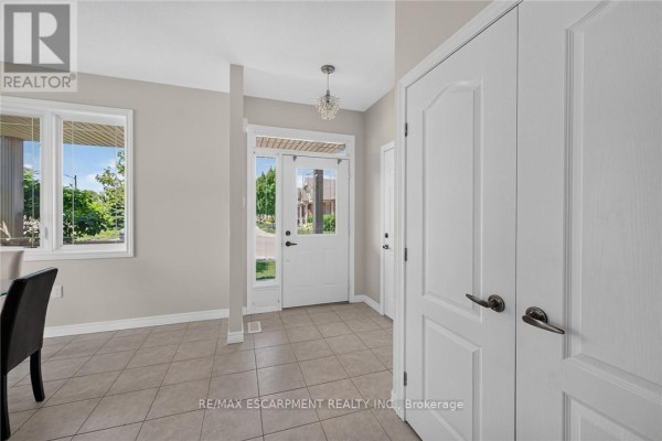 Interior view of the entryway with white doors, tiled floors, and a window overlooking the street. - 14 Ecker Lane, Hamilton