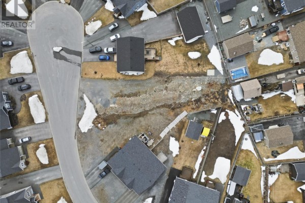 Top-down aerial view of a curved street and surrounding houses with undeveloped land. - 14 Esmonde Place, Gander