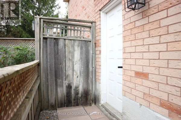 Wooden privacy fence next to a brick wall and a white exterior door. - (bsmt) - 14 Genner Drive, Ajax