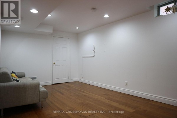 Empty basement room with hardwood floors, white walls, recessed lighting, and one door. - (bsmt) - 14 Genner Drive, Ajax