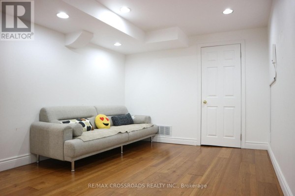 Basement room with hardwood floors, white walls, recessed lighting, and a grey sofa. - (bsmt) - 14 Genner Drive, Ajax