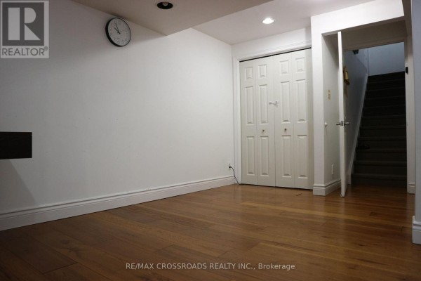Basement room with hardwood floors, white walls, recessed lighting, bi-fold closet doors, and staircase. - (bsmt) - 14 Genner Drive, Ajax