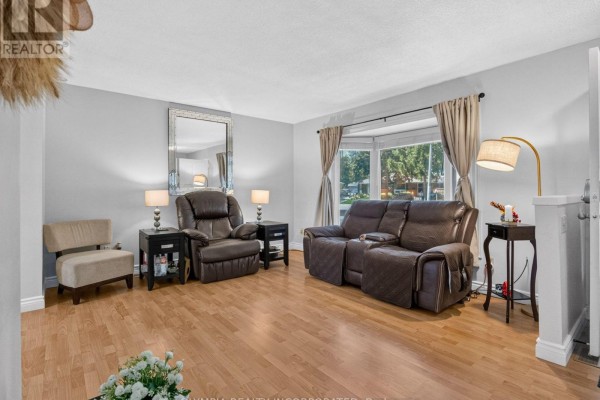 Living room with brown leather recliners, a bay window, and wood flooring. - 14 Hill Park Lane, St  Catharines