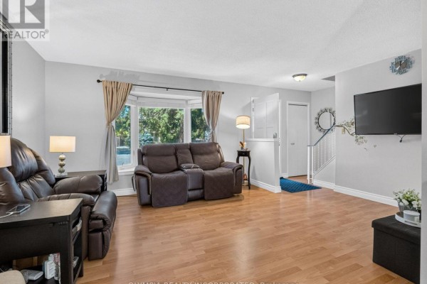 View of the living room, showing furniture, a bay window, and the entrance to the staircase. - 14 Hill Park Lane, St  Catharines