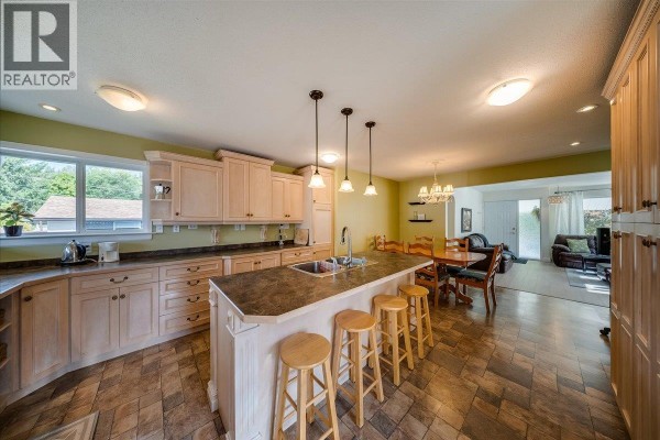 Open concept kitchen with light wood cabinets, large island, and view of dining and living areas. - 14 Hillside Drive, Trail