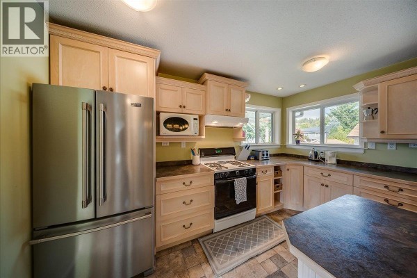 Kitchen featuring stainless steel refrigerator, gas stove, microwave, and light wood cabinetry. - 14 Hillside Drive, Trail
