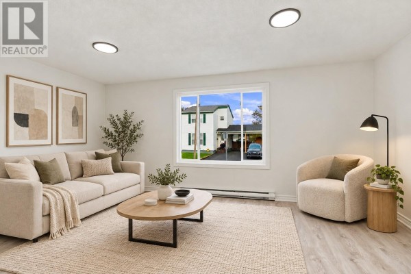 Living room with a sofa, armchair, coffee table, rug, and a large window with exterior view. - 14 Jubilee Place, Mount Pearl