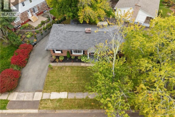Aerial view of the red brick bungalow showing the roof, yard, and neighboring houses. - 14 Laird, Moncton