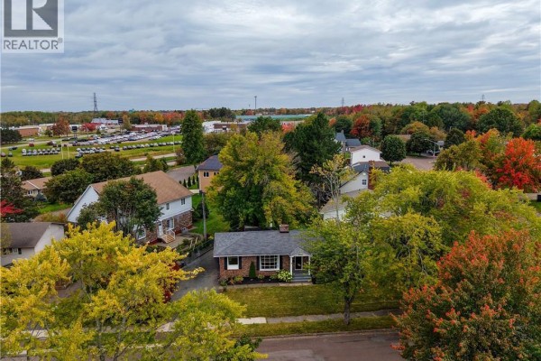 Overhead drone view of the bungalow surrounded by colorful autumn trees and neighboring properties. - 14 Laird, Moncton