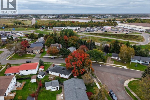 Elevated view of the neighborhood with houses, trees displaying fall foliage, and distant commercial buildings. - 14 Laird, Moncton