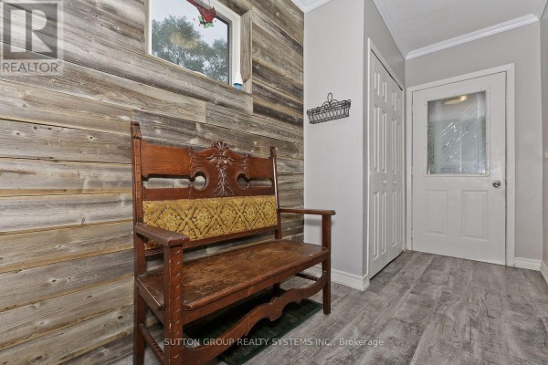 Interior hallway with wood-planked wall, antique bench, double door, and a small window. - 14 Lake Shore Drive, Toronto