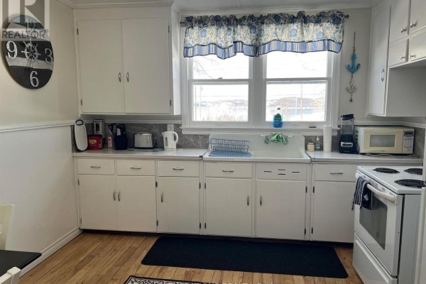 White kitchen with white cabinets, a double sink, a stove, and a window overlooking a body of water. - 14 Mccullough Street, Marathon