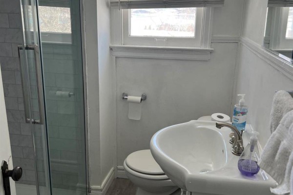 Bathroom with a white sink, toilet, and a glass-enclosed shower with subway tiles. - 14 Mccullough Street, Marathon